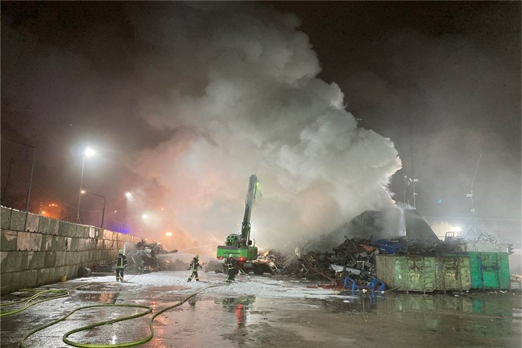 Großbrand in Herten-Süd: Feuerwehr warnt – Rauch zieht bis nach Recklinghausen Auf einem Schrottplatz an der Straße Im Emscherbruch brennt ein Schrotthaufen. Ein Baggerfahrer hilft den zahlreichen Einsatzkräften bei den Löscharbeiten.