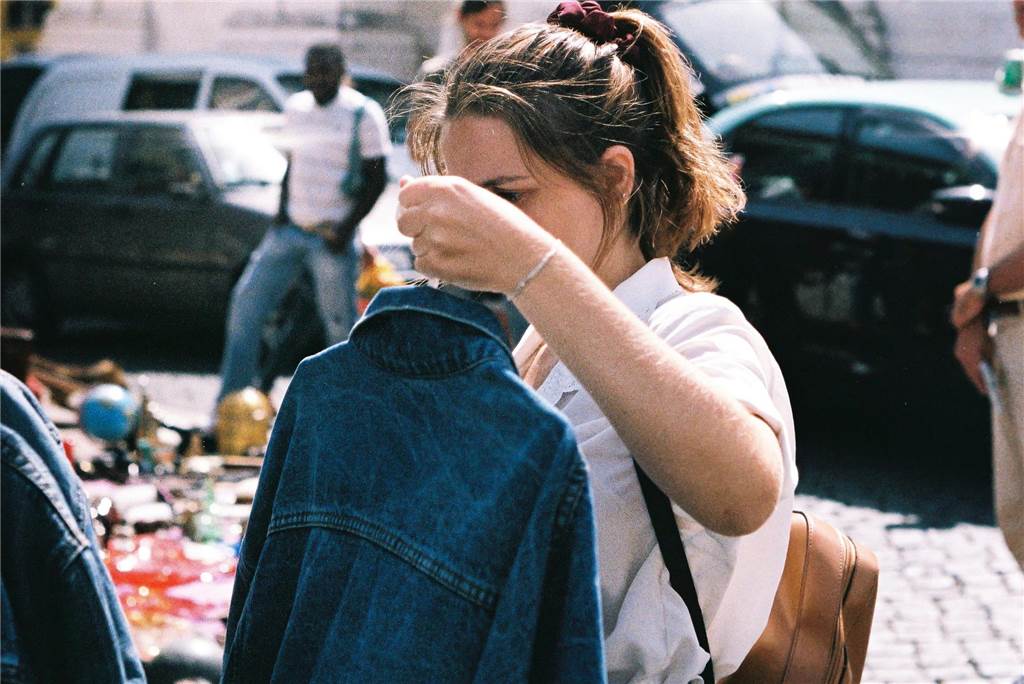 Trödelmarkt in NRW am Wochenende: Wo ist am 3. und 4. Mai 2025 Flohmarkt? Eine Frau hält auf einem Trödelmarkt in NRW eine Jeansjacke in der Hand.