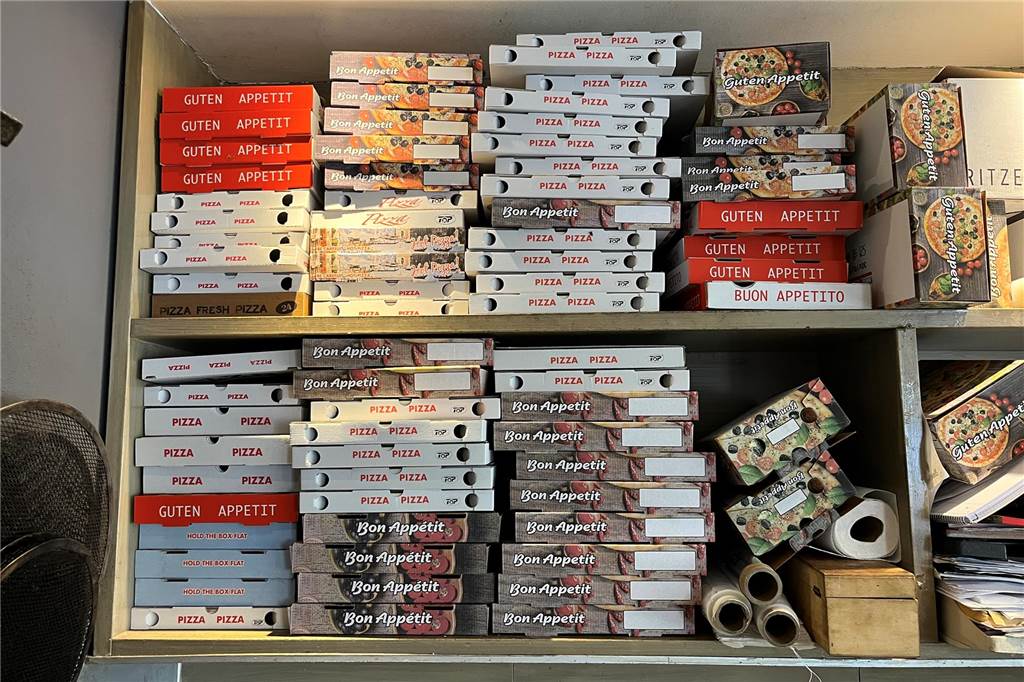 Bürger will Extra-Steuer für Einwegverpackungen in Lünen Ein Regal mit Pizzakartons.