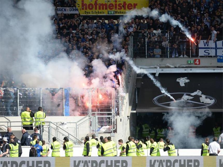 Aus dem Gästeblock beim VfB Stuttgart werden Feuerwerkskörper von KSC-Fans auf das Spielfeld geworfen. Foto: Deniz Calagan