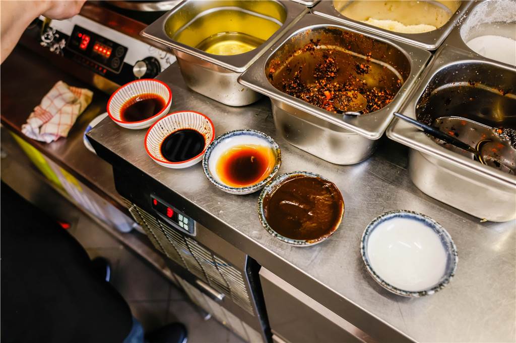 Chinesischer Koch zeigt Lieblingsessen: Fingerfood mit süßer Sojacreme Aus diesen Bestandteilen wird die Sojacreme hergestellt: Salzige und süße Sojasauce, Austernsauce, etwas Zucker (ganz rechts und schon in der Pfanne) und Sojapaste.