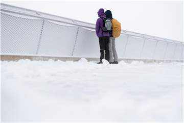 Ausflügler stehen auf dem Gipfel der Zugspitze auf der Aussichtsplattform im Schnee. Foto: Sven Hoppe