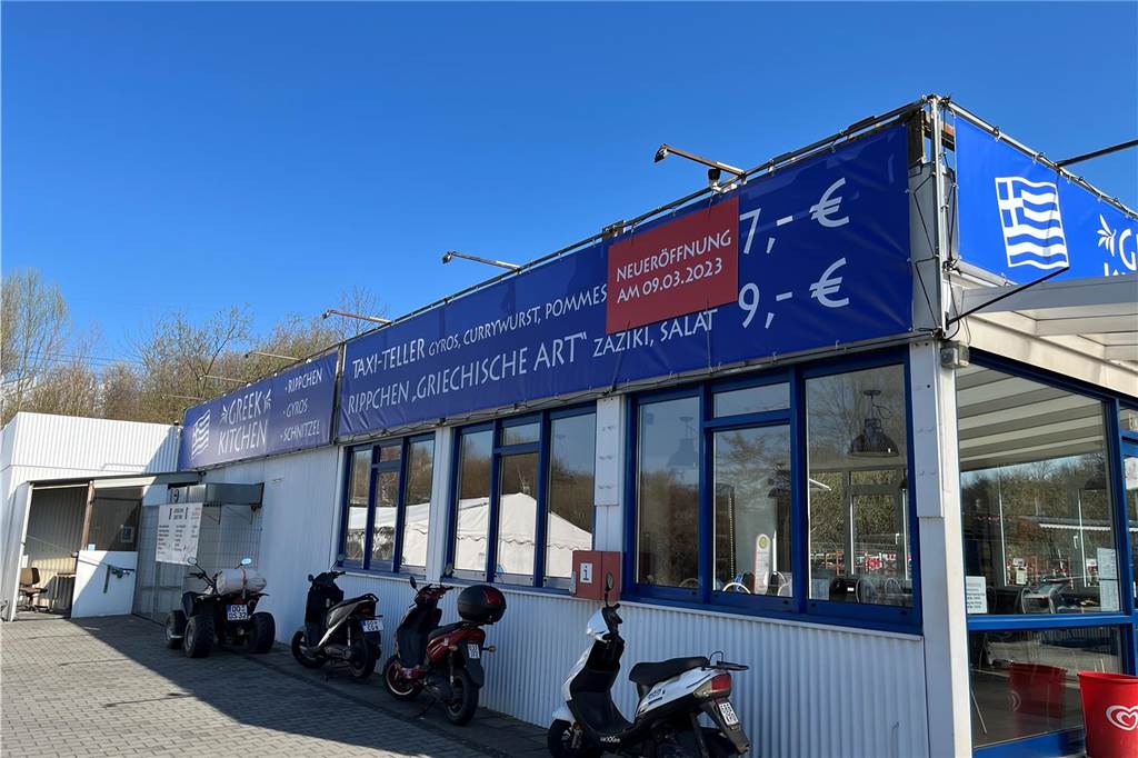 „Greek Kitchen“: Neues Schnellrestaurant auf S+E-Gelände gut gestartet Außen an ihrem Restaurant werben Anastasia Cigonitrou und Panagiotis Mouratidis für den Taxi-Teller