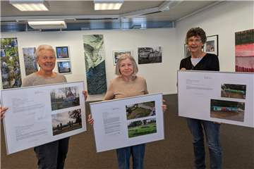 Drei Frauen halten Bilder in der Hand.