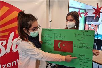 Avsin (links) erklärt, dass sich die Türkei auf den Kontinenten Asien und Europa befindet. Sprachlernbegleiterin Carina Eller hält das Plakat.