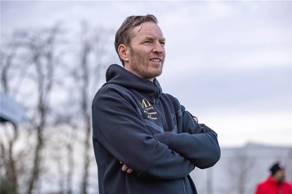 Schmeing blickt mit verschränkten Armen aufs Spielfeld.