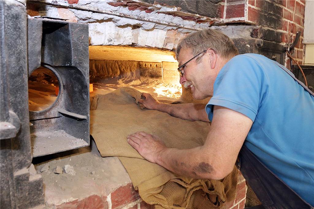 Neue Steine für historischen Backofen bei Balke: Handwerker geben alles Backofenbauer Claus Heuft muss in den Backofen kriechen, um die Verlegung der neuen Tuffsteine vorzubereiten.