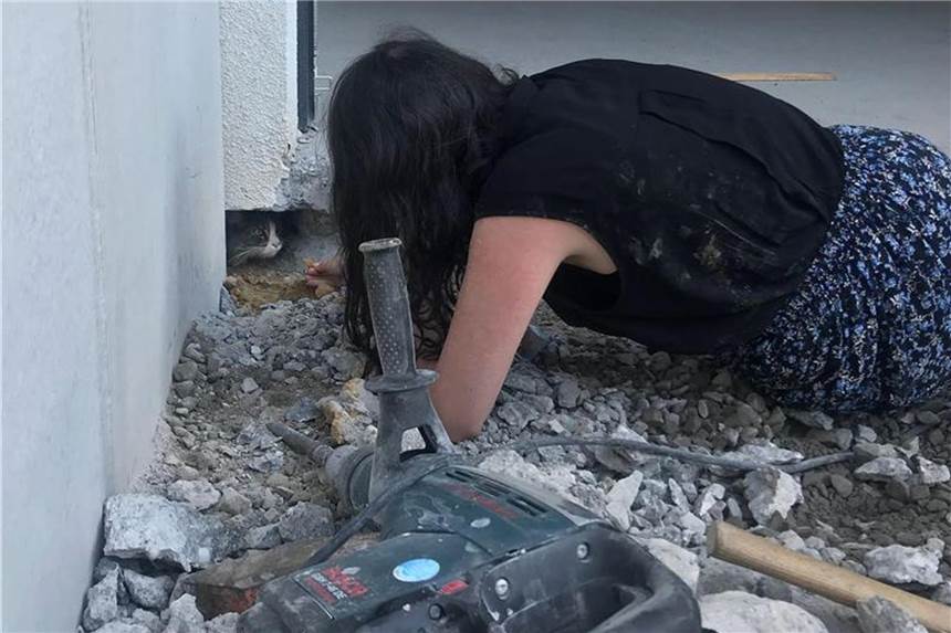 Bauarbeiter hatten Kater Jimmy versehentlich unter einer Fertiggarage einbetoniert. Hier die Besitzerin bei dem versuch das Tier wieder herauszulocken. Foto: Polizeipräsidium Karlsruhe