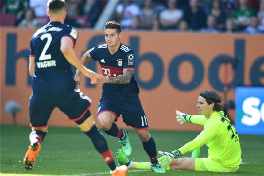 FC Bayern feiert 28. Meistertitel - „Das schönste Erlebnis“ Bayerns James Rodriguez (M) erzielt den Treffer zum 2:1 gegen den bereits geschlagenen FCA-Torwart Marwin Hitz (r). Foto: Sven Hoppe