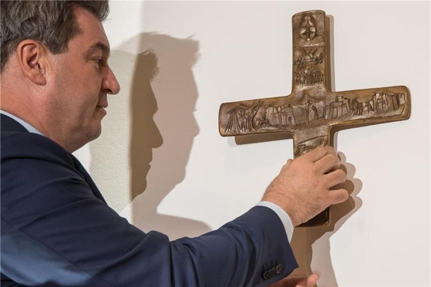 CSU verteidigt bayerische Kruzifix-Pläne Bayerns Ministerpräsident Markus Söder hängt ein Kreuz im Eingangsbereich der bayerischen Staatskanzlei auf. Foto: Peter Kneffel