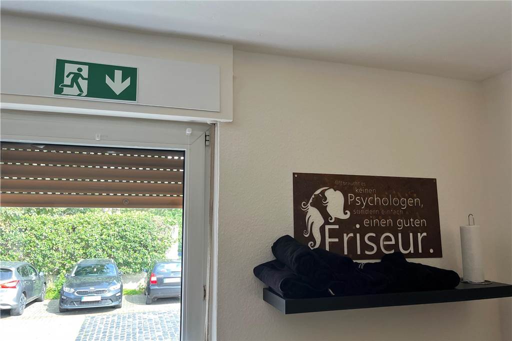 Nina Pawlowski schneidet Haare im Salon in ihrem ehemaligen Wohnzimmer Behördliche Auflage: Über einem Fenster im "Wohnzimmerfriseursalon" von Nina Pawlowski hängt ein Notausgangsschild.