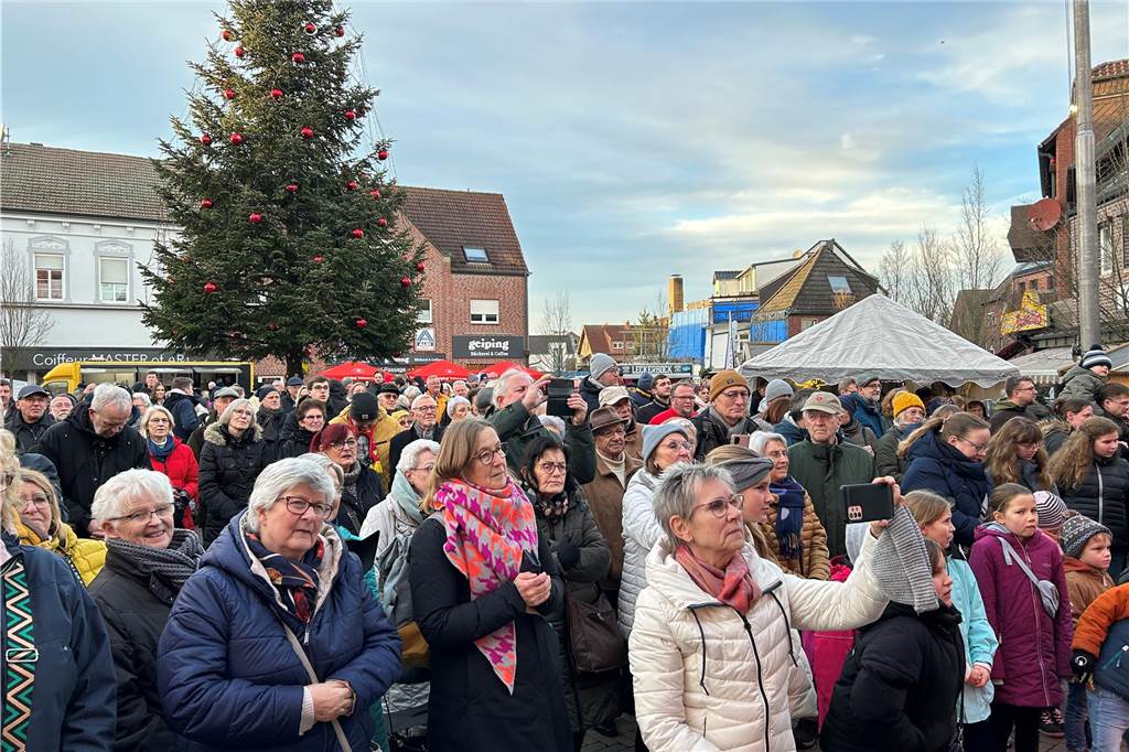 Hannelore Frie erhält den Bürgerpreis bei stimmungsvollem Weihnachtszauber Viele Menschen stehen auf dem Marktplatz mit dem Weihnachtsbaum und schauen auf die Bühne.