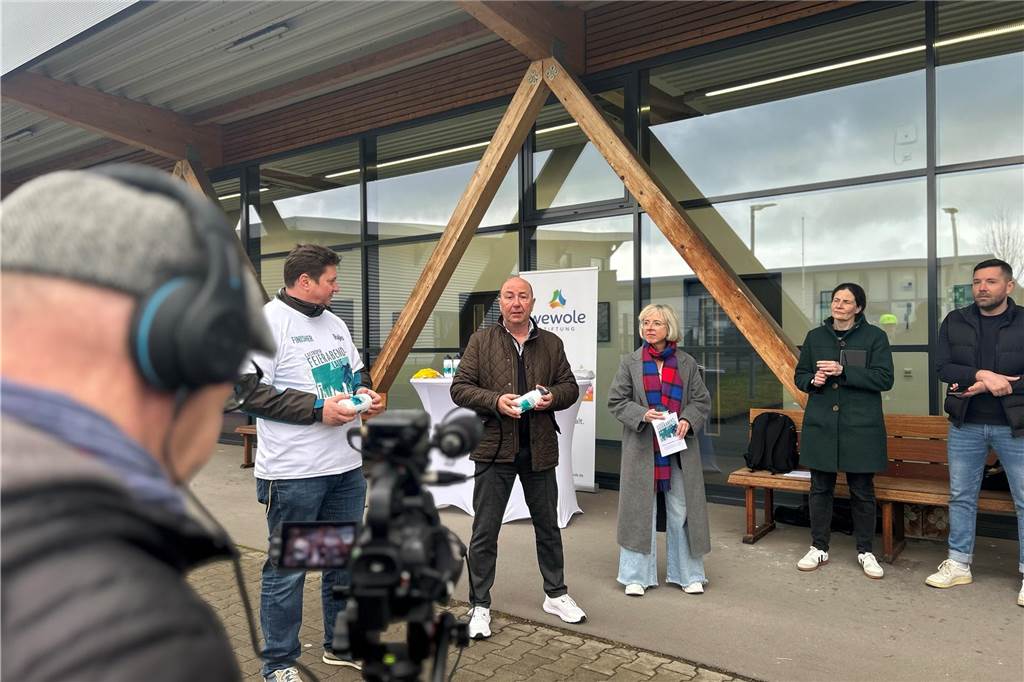 Wolfgang Heller, Anne Krüger und der Bürgermeister der Stadt Castrop-Rauxel stehen in einem Kreis. Im Vordergrund ist ein Kameramann zu sehen, der die Aktion filmt. 