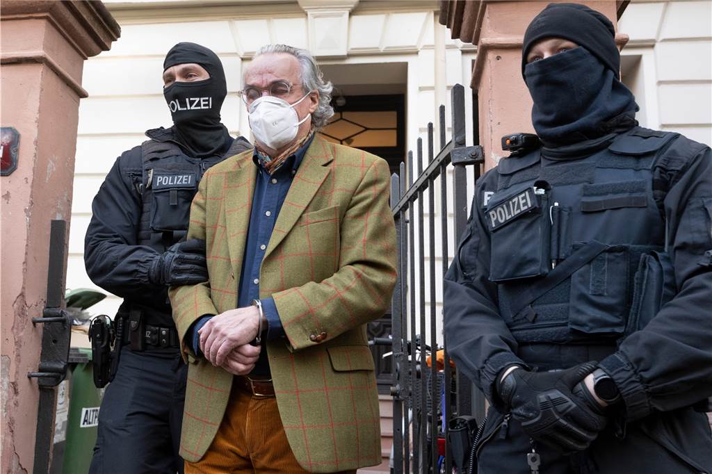 Heinrich XIII Prinz Reuß wird von zwei maskierten Polizisten in Handschellen abgeführt.