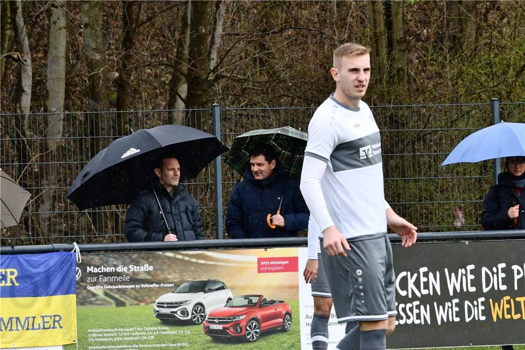 Lars Müller (l.) steht mit Regenschirm am Rand. Im Fokus: WSC-Spieler Nico Holtmann.