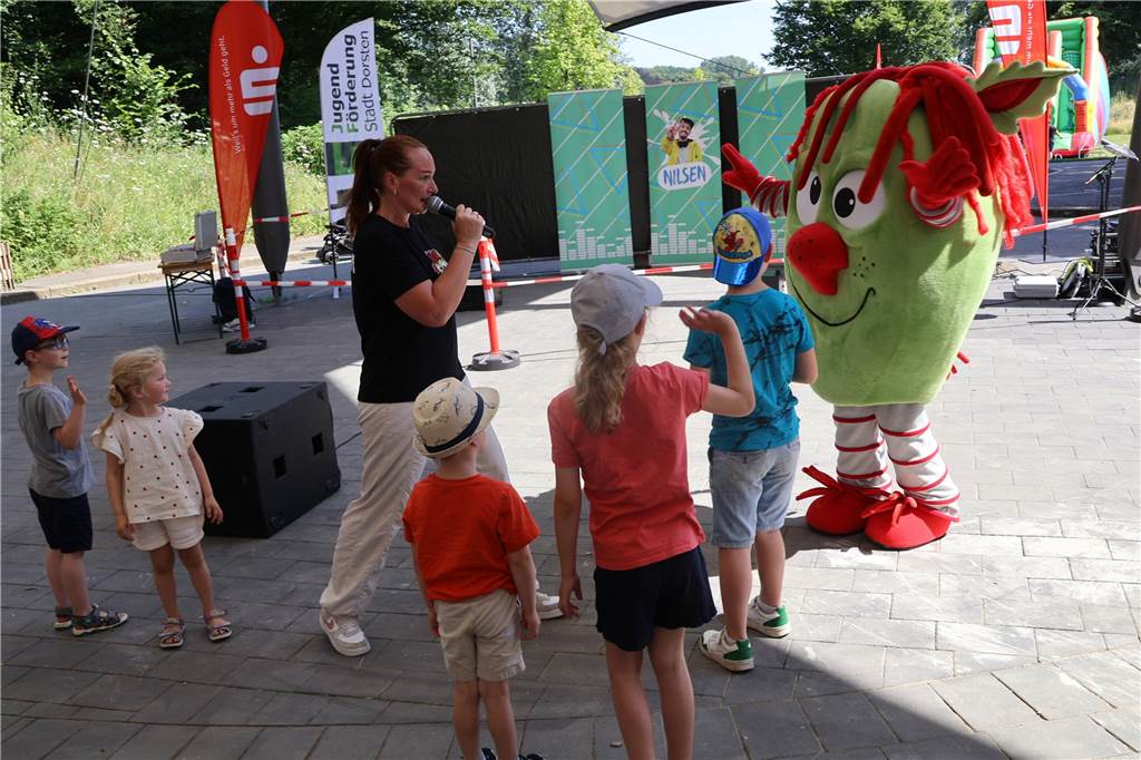 Unterstützung für Stadtfeste und Co. geht weit über Finanzielle hinaus Mehrere Kinder stehen im Bürgerpark Maria Lindenhof um eine Sängerin herum.