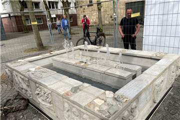 Sprudelnder Brunnen mit Passanten.