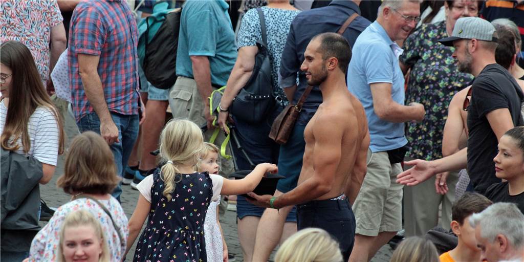 Mit vielen Bildern: Zuschauer und Stadtmarketing sind begeistert vom Straßenfestival Kinder geben eine Spende in den Hut eines Künstlers.