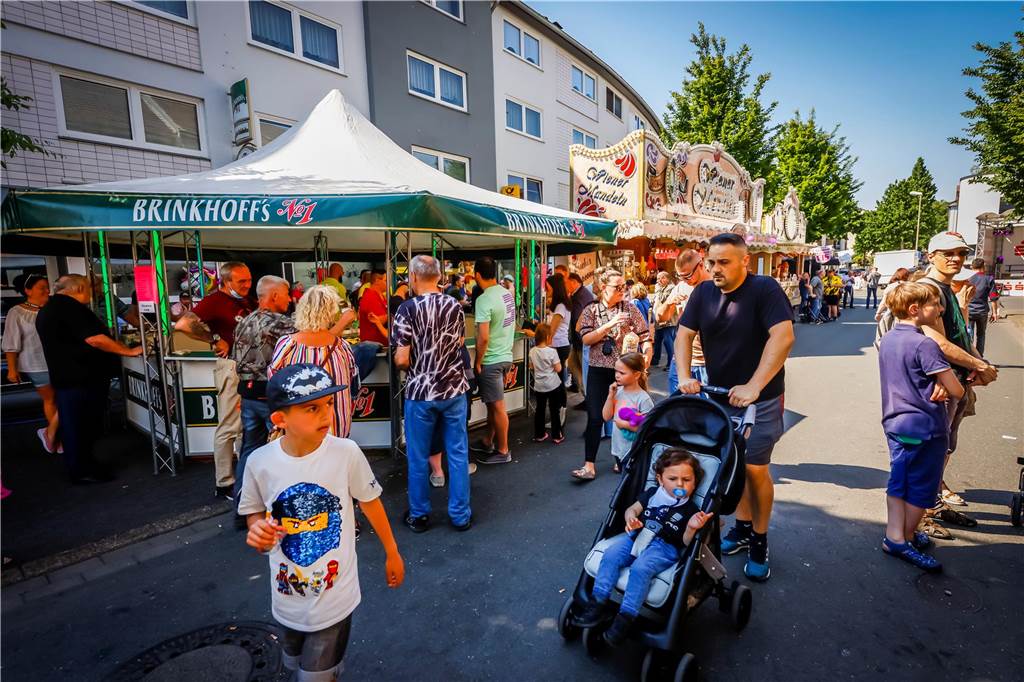 Kirmes in Huckarde: Fünf Gründe für den Besuch der „Pingsthuekke“ Ein Mann bummelt mit Kindern durch die Budengasse. Im Hintergrund ein Bierstand.