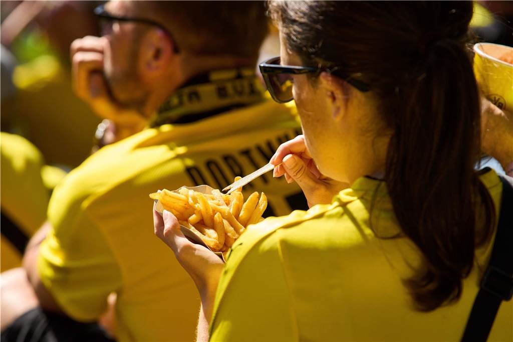 BVB nur auf Platz zwei hinter Schalke: Bundesliga-Ranking zum Essens-Angebot im Stadion Eine Frau piekst mit einer Gabel in ihre Pommes.