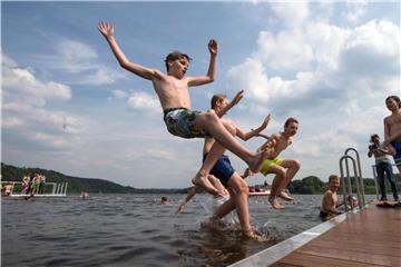 Ben, Micha, Luca und Luca springen von einem neuen Steg in den Baldeneysee. Seit der Saisoneröffnung am 6. Mai konnte bereits an 22 Tagen in der Ruhr gebadet werden. Foto: Bernd Thissen/Archiv