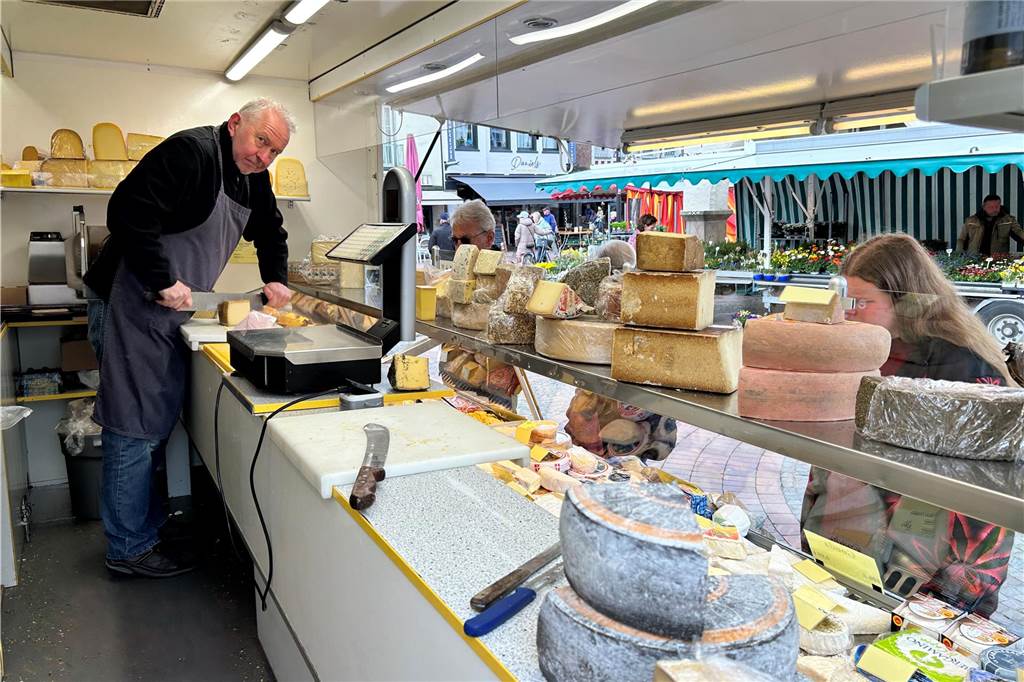 Ein Käseverkäufer steht hinter dem Tresen auf dem Wochenmarkt