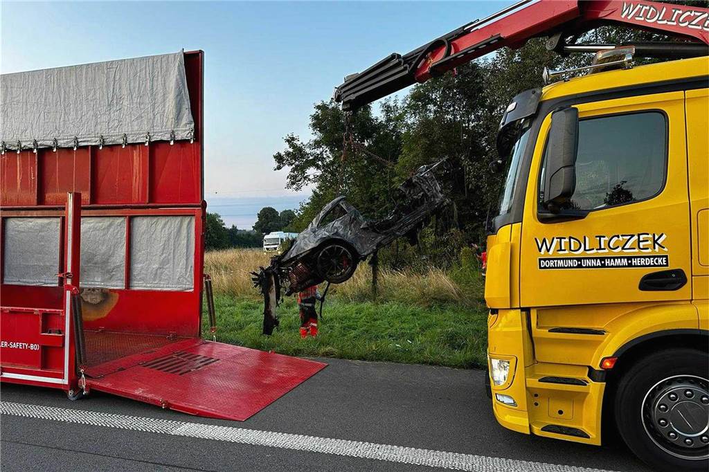 Bergungsarbeiten an der A44. Ein Kran hebt das ausgebrannte Porsche-Wrack.