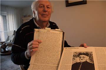 Bernhard Wilms zeigt Aufzeichnungen aus der Pfarrchronik von 1945 und ein Bild des Pfarrers Gerhard Harrier.