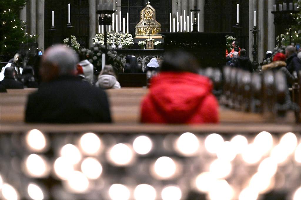 Besucher des Kölner Doms verfolgen eine Messe. 