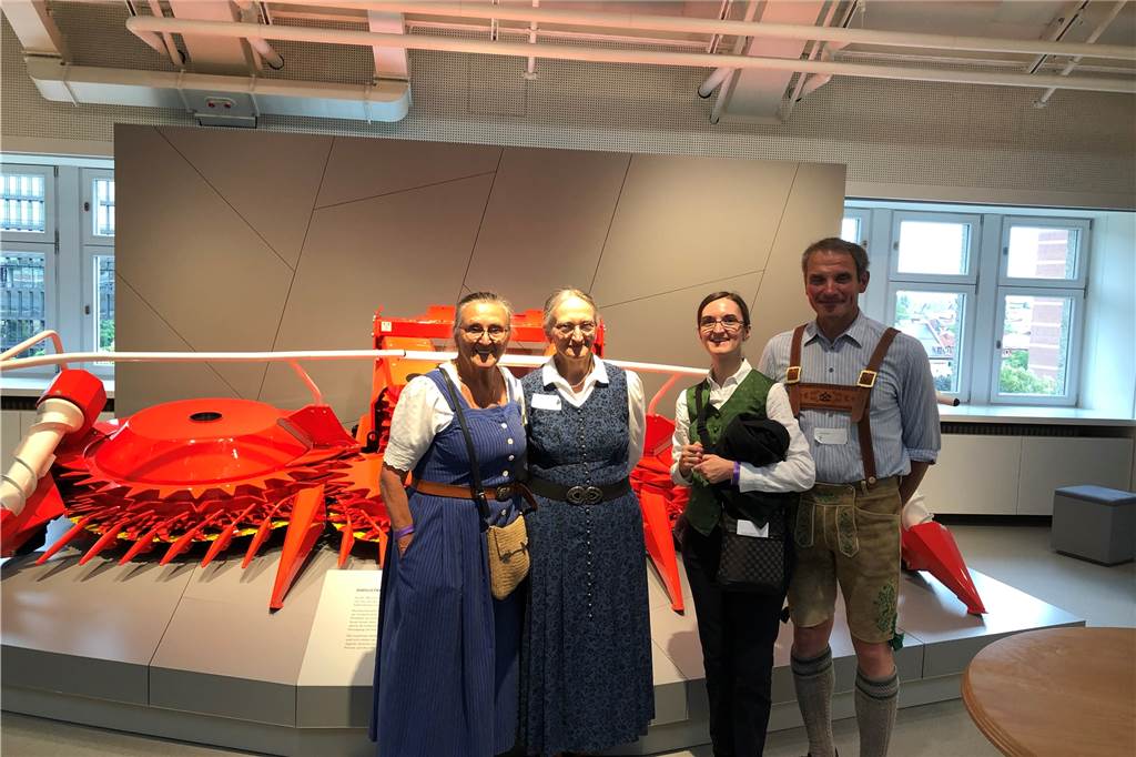 Besucher in bayrischen Trachten vor dem Kemper-Mähvorsatz im Deutschen Museum in München.