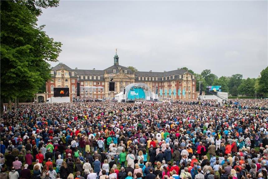 Besucher stehen zum Start der Eucharistiefeier zum Gottesdienst zu Christi Himmelfahrt auf dem Schlossplatz in Münster. Foto: Guido Kirchner