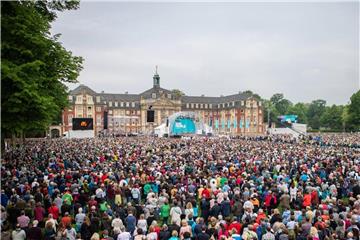 Besucher stehen zum Start der Eucharistiefeier zum Gottesdienst zu Christi Himmelfahrt auf dem Schlossplatz in Münster. Foto: Guido Kirchner