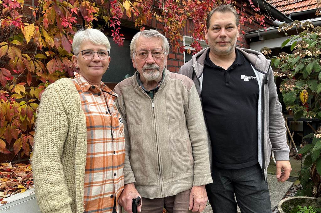 Urgestein des Wochenmarkts: Sturmhart Schinkel war von Anfang an dabei Älterer Mann mit Gehstock steht zwischen einer Frau und einem Mann vor einem Haus, an dem Rot-Gelbe Blätter runterhängen.