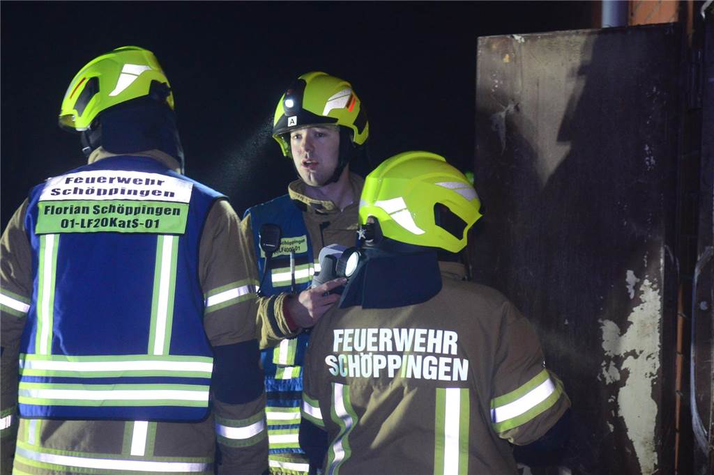 Im Schweinestall brennt es Ein Feuerwehrmann spricht mit zwei anderen Feuerwehrleuten.