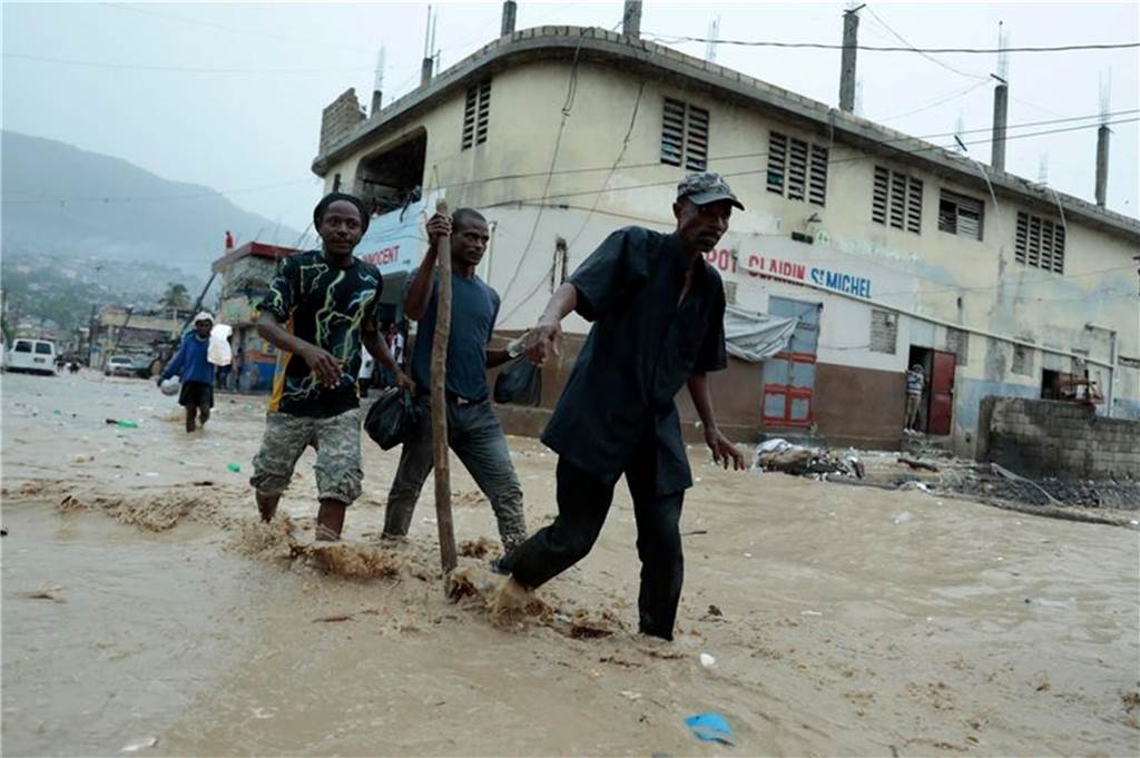 Überschwemmungen in Haiti: 42 Tote, 14.000 Menschen evakuiert Bewohner waten über eine überschwemmte Straße nach einem starken Regen in Port-au-Prince. Foto: Odelyn Joseph/AP