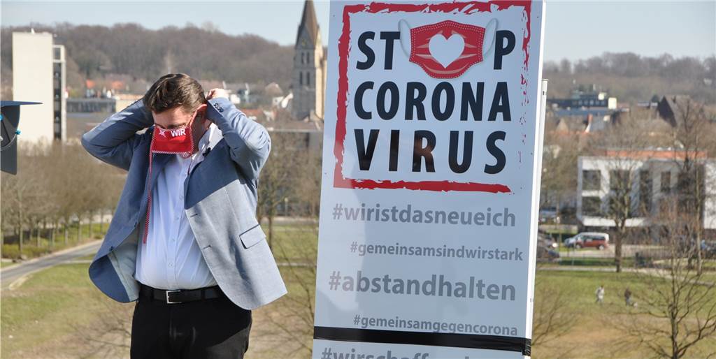 Ein Sinnbild für die Corona-Pandemie: Castrop-Rauxels Bürgermeister Rajko Kravanja bindet sich auf einem der Hügel des Erin-Parks einen Mund-Nasen-Schutz um. Die Roten Masken sind zu einer Art Symbol für die Europastadt geworden.