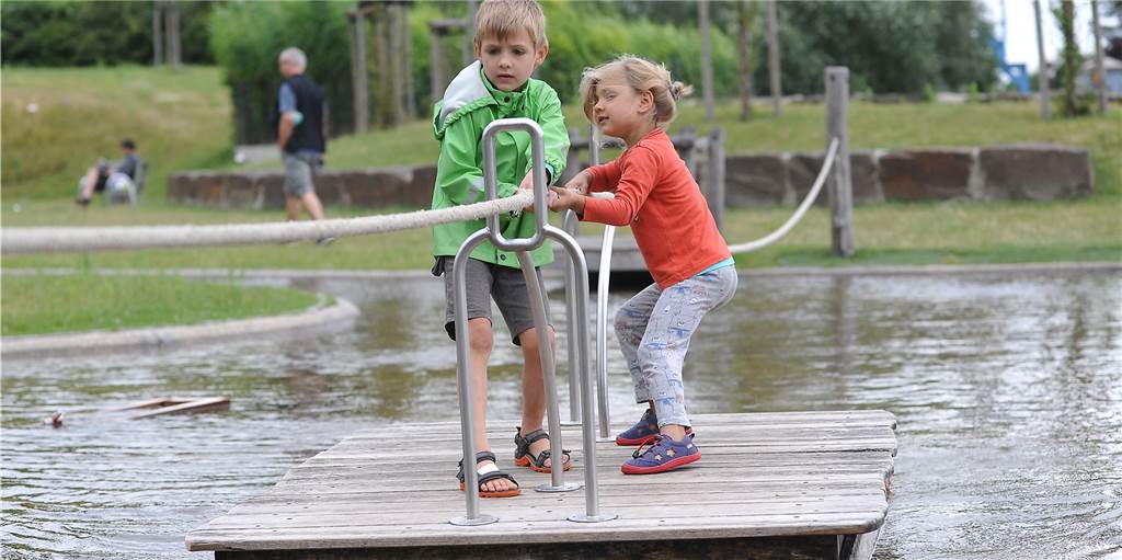 Spielen, gucken und lernen: Ein Tag am Schiffshebewerk Henrichenburg Mit vereinten Kräften schaffen es auch jüngere Kinder, das Floß gut über den künstlichen See des Wasserspielplatzes am Schiffshebewerk Henrichenburg zu ziehen.