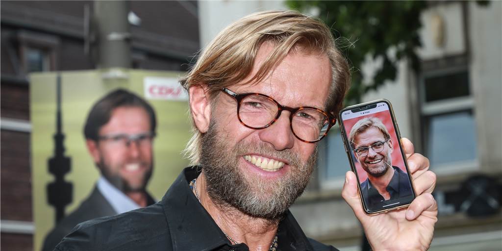Wahlplakate im Kreuzviertel: Ist Jürgen Klopp plötzlich Politiker? Wer ist wer? Auf dem Plakat im Hintergrund und vorne am Handy: Markus Bartel. Auf dem Handy: Jürgen Klopp.