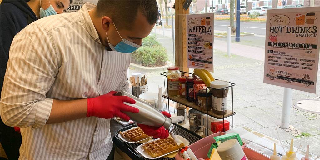 Münsterstraße statt Weihnachtsmarkt: Waffel-Bude eröffnet in der Nordstadt Torty’s-Chef David Kremer (vorne) legt im Waffelstand an der Münsterstraße selber Hand an und sagt, er habe schon einige Waffeln verkauft.