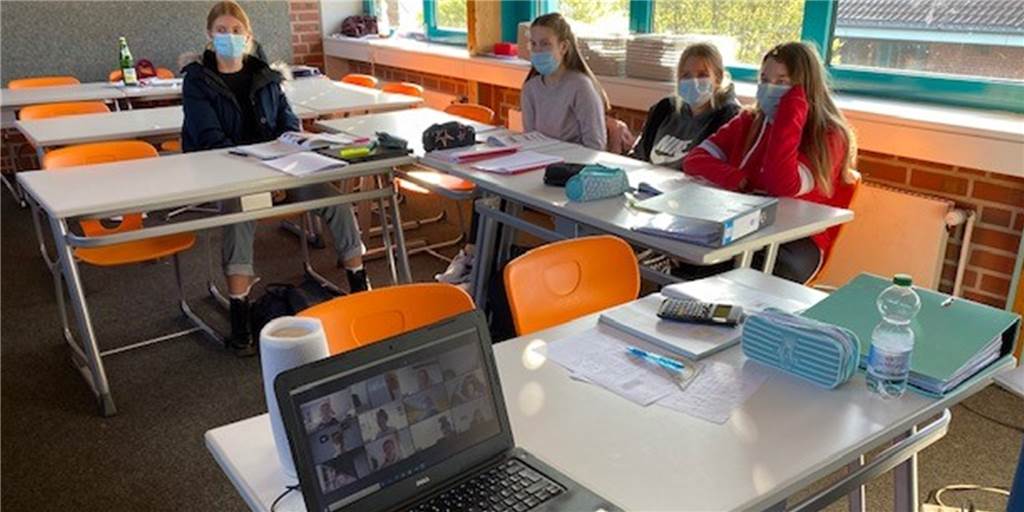 Die meisten Schüler sitzen im Klassenraum, doch einige Mitschüler sind "nur" virtuell dabei. Sie sind in Quarantäne, können aber dennoch am Unterricht teilnehmen.
