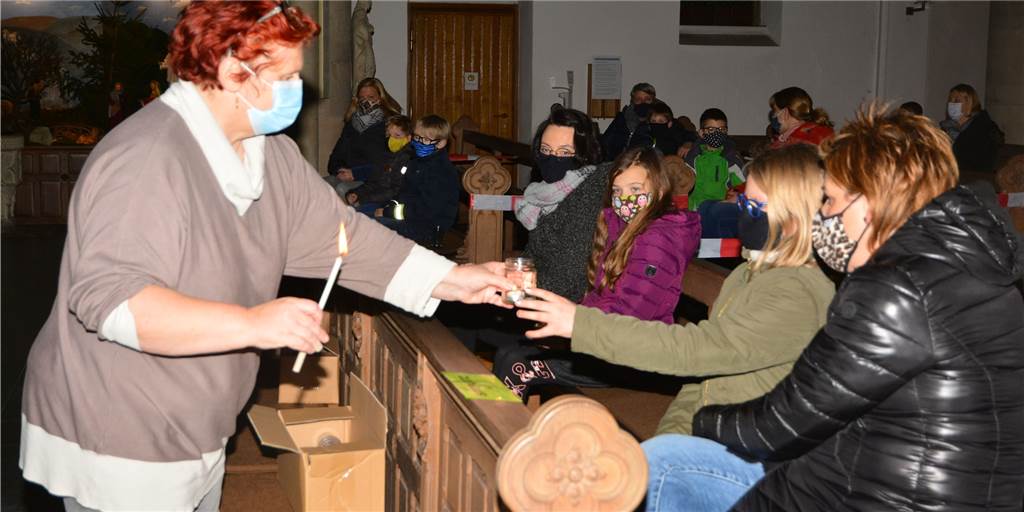 Heilig Kreuz Heek: Erstkommunionkinder empfangen Friedenslicht aus Bethlehem Pastoralreferentin Mechtild Sicking zündet die Kerzen an.