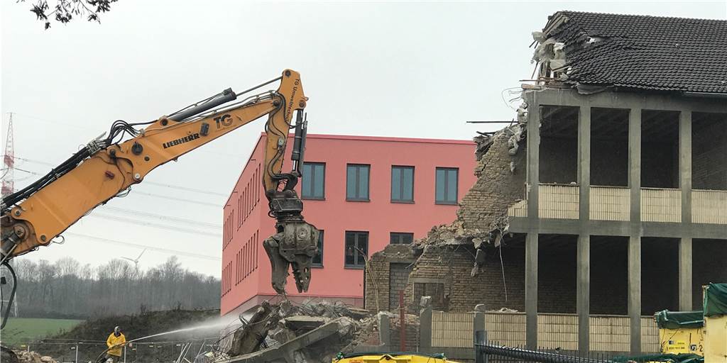 Gegen den Staub wird mit Wasser gespritzt: Ein Abrissbagger sorgt dafür, dass der Blick von der Straße Im Odemsloh den Blick freigibt auf den Neubau der Reinoldischule. Seit Frühjahr 2020 wird dort unterrichtet.