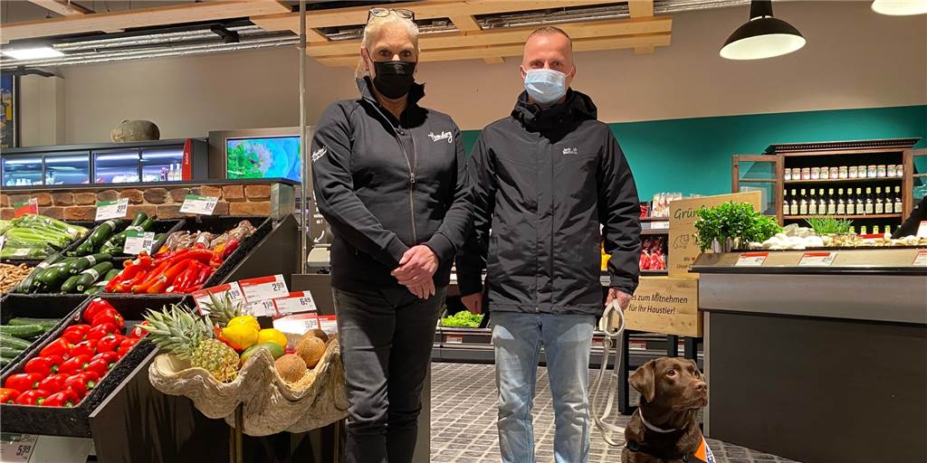 Martina Homberg-Budnik (l.) freut sich über den „Assistenzhund Willkommen“-Aufkleber für ihr Geschäft. Thorsten Habel (r.) macht die Dortmunder Händler aufmerksam auf die Aktion und bringt die Aufkleber auch persönlich vorbei – zusammen mit seiner Assistenzhündin Hanni.