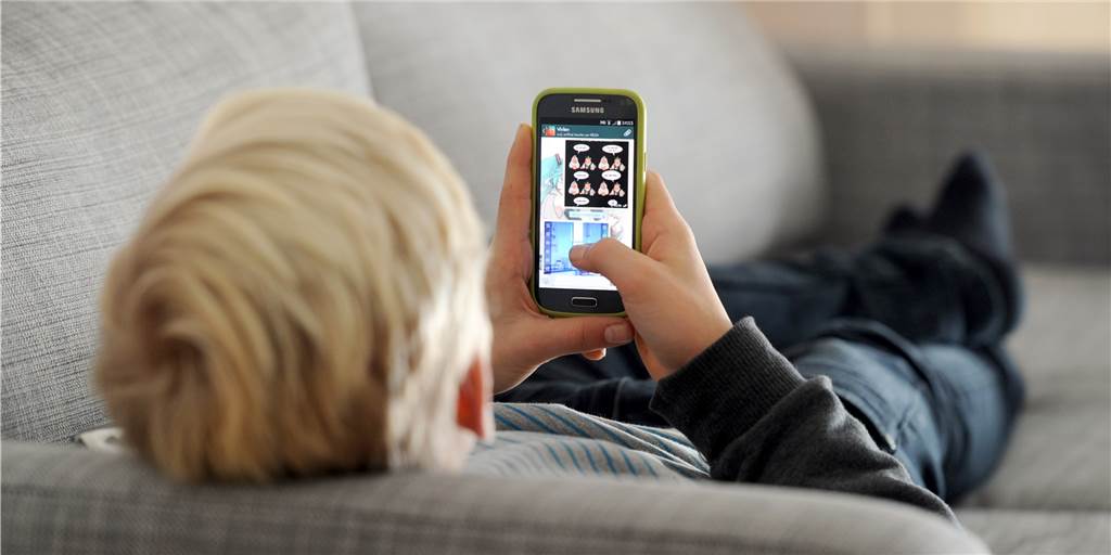 Frohe Freundin und gemütliches Sofa: Kehren Kinder nach Corona nicht mehr in ihre Sportklubs zurück? Im Moment müssen Kinder gezwungenermaßen viel Zeit auf der Couch verbringen. Kommen sie davon aber hoch, wenn wieder Sport gemacht werden kann?
