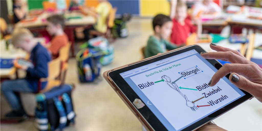 Digitalunterricht: „Lehrer haben dank Digitalisierung gar nicht mehr frei“ Eine Lehrerin bedient in einer Grundschul-Klasse ein Tablet. Digitale Anwendungen halten immer stärker Einzug in den Unterricht. (Symbolbild)