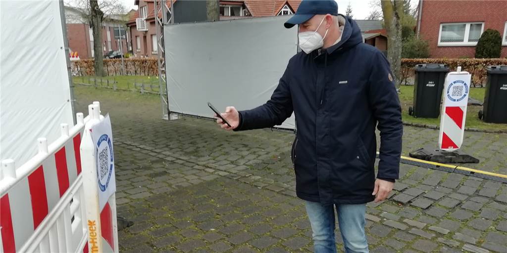 Bürgermeister Weilinghoff freut sich über neue Corona-Teststation in Heek An der am Samstag eröffneten Teststation am Markplatz scannt Bürgermeister Franz Josef Weilinghoff zur Anmeldung den QR-Code ein.