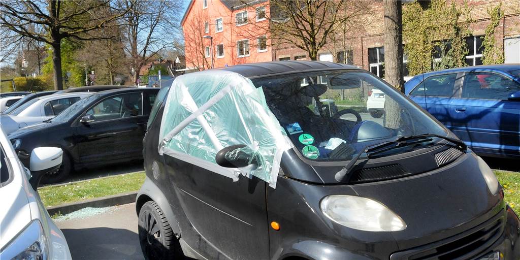 Reihenweise Autos geknackt: Täter gingen mit Brachialgewalt vor Notdürftig mit Plastikfolie geflickt ist die Seitenscheibe dieses Kleinwagens auf dem Parkplatz Im Reiche des Wassers. In seinem Innenraum und auf dem Asphalt sind überall Splitter vom Sicherheitsglas verstreut.