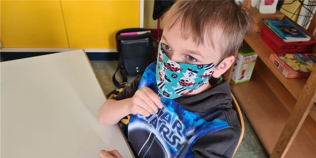 Osterfeldschule Lünen: Lolli-Tests werden Routine für Erstklässler Dominik schiebt das Teststäbchen unter der Maske hindurch in den Mund. 30 Sekunden müssen seine Klassenkameraden und er auf dem Stäbchen lutschen, ehe es von den Lehrkräften eingesammelt wird.