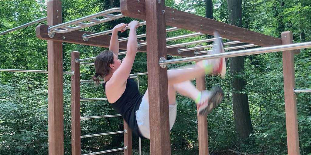 Hannah Wolf demonstriert bei der Eröffnung, wie die Sportgeräte des Calesthenics-Parcours im Volkspark Schwansbell genutzt werden können. Als Freiraumplanerin der Stadt Lünen hat sie auch bei der Umgestaltung entscheidend mit angepackt.