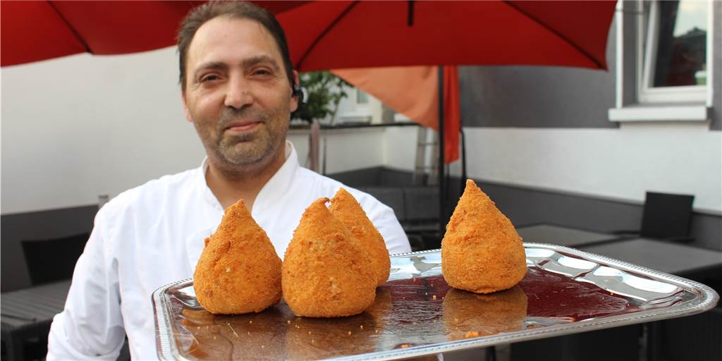 Auf der frisch ausgebauten Terrasse hat Aldo Rifati einen Biergarten eingerichtet. Auf dem Tablett zeigt der Wirt sizilianisches Fingerfood: Arangina, Reiskroketten mit leckerer Füllung.